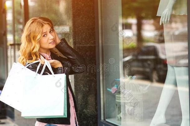 惊愕的年幼的女士和购物袋,有样子的通过商店风