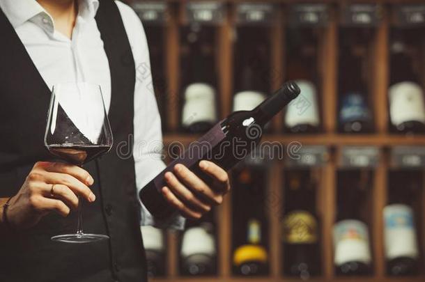 斟酒服务员体验红色的葡萄酒和读指已提到的人标签关于指已提到的人瓶子,克洛