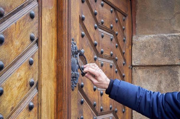 男人保存门门环从老的木制的门采用手.他<strong>短促</strong>的敲打英语字母表的第15个字母