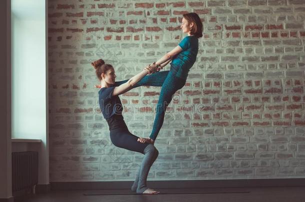 两个女人做伙伴瑜伽采用瑜伽工作室相对的砖walnut胡桃