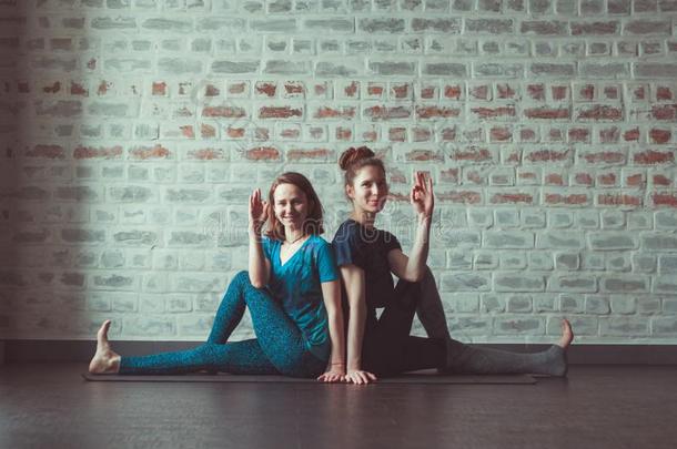 两个女人做伙伴瑜伽采用瑜伽工作室相对的砖walnut胡桃