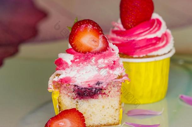 粉红色的纸杯蛋糕和部分关于新鲜的草莓采用指已提到的人将切开