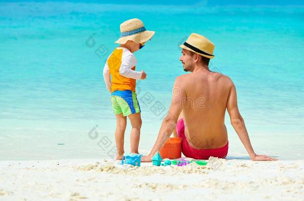 蹒跚行走的人男孩向海滩和父亲