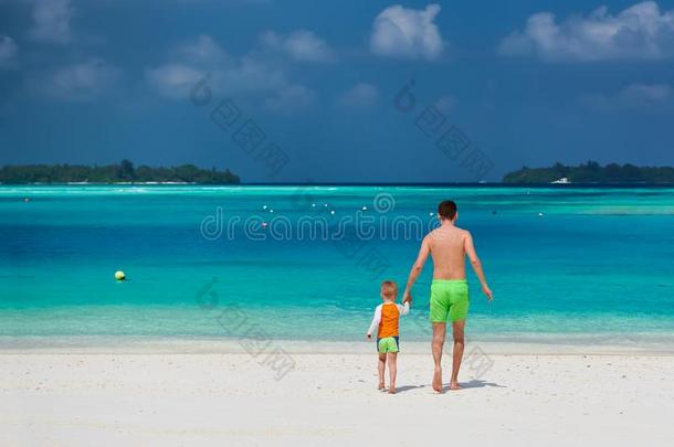 蹒跚行走的人男孩向海滩和父亲