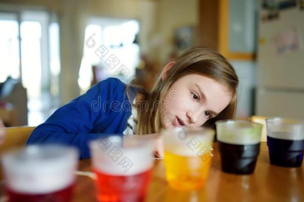 漂亮的年幼的女孩染色复活节卵在家.小孩绘画颜色