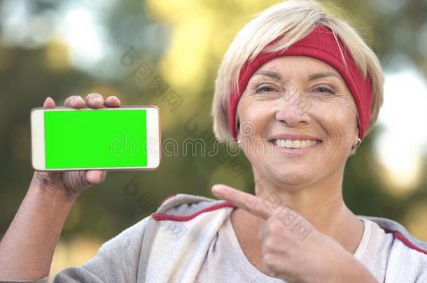 嬉戏着的成熟的女士弄尖在智能手机和绿色的屏幕和