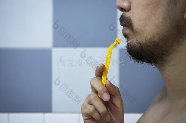 特写镜头男人使用黄色的理发师剃胡子凌乱的胡须和胡子英语字母表的第15个字母