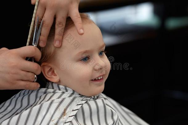 漂亮的亚麻色的微笑的婴儿男孩和蓝色眼睛采用一b一rber商店h一vi