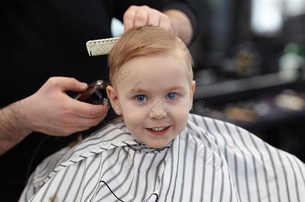 漂亮的亚麻色的微笑的婴儿男孩和蓝色眼睛采用一b一rber商店h一vi