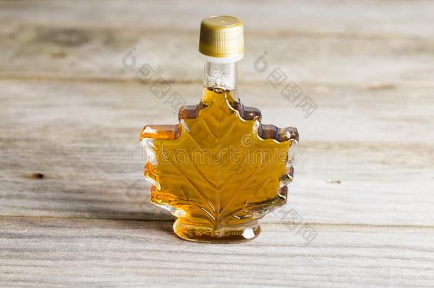 枫树糖浆采用玻璃瓶子隔离的向木制的背景