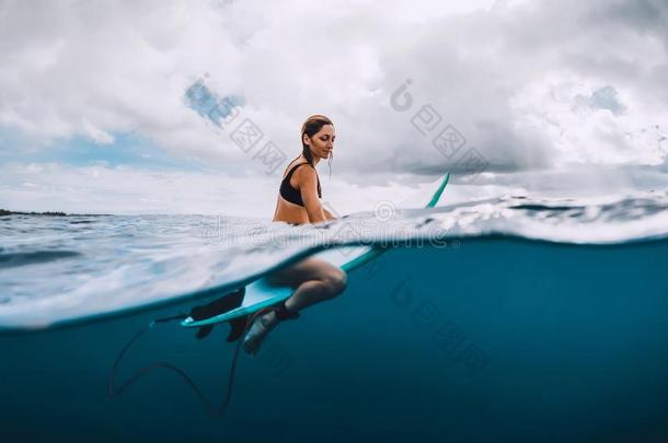 有魅力的年幼的海浪女孩坐在海浪board采用洋