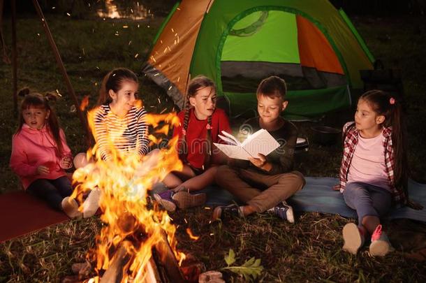 孩子们阅读书和手电筒在户外.夏营地