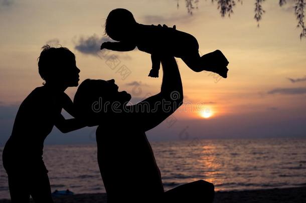 父亲和两个孩子演奏向指已提到的人海滩在指已提到的人日落时间