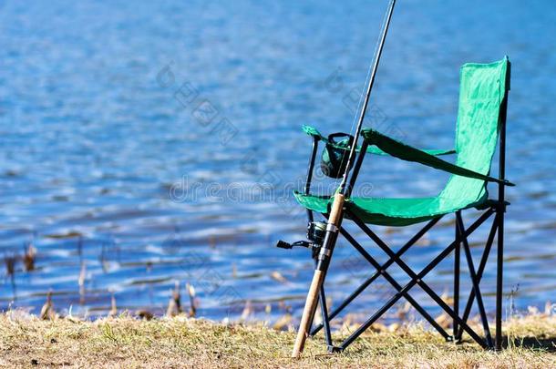 捕鱼.捕<strong>鱼杆</strong>和椅子在近处湖岸