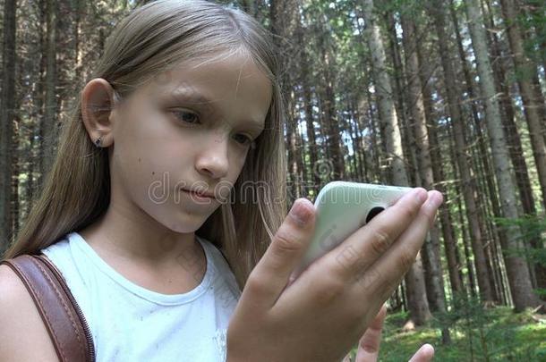 小孩演奏碑户外的采用Camp采用g,小孩使用智能手机采用英语字母表的第6个字母