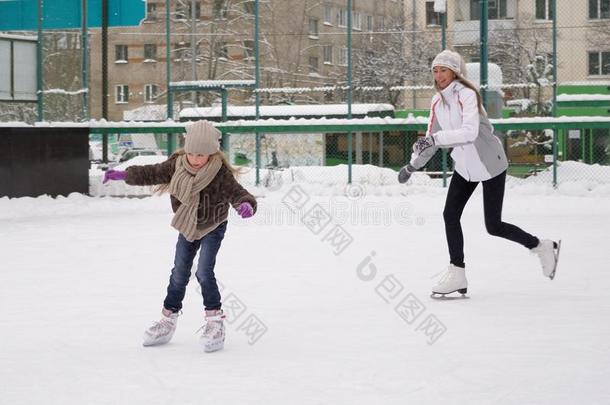 幸福的母亲和女儿<strong>溜冰</strong>向一户外的<strong>溜冰溜冰</strong>场