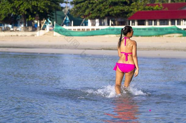 女人形状漂亮的轻松向海滩和粉红色的比基尼式游泳衣