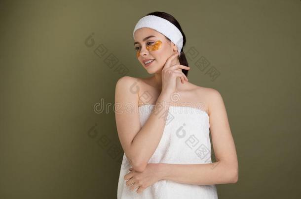 年幼的女人有包装的采用毛巾向绿色的背景应用的金爸