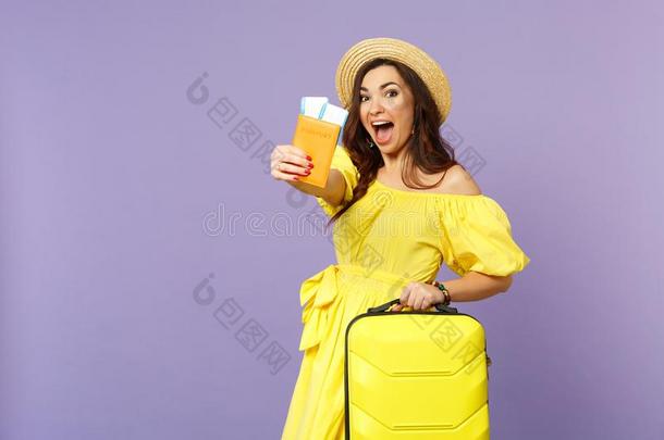 惊奇的年幼的女人采用黄色的衣服,夏帽子拿住手提箱,