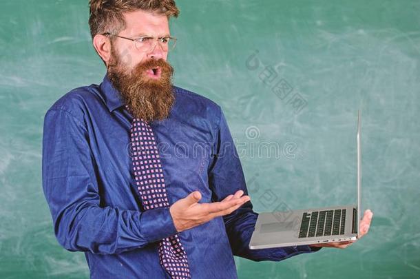教师有胡须的男人糊涂的使工作和现代的便携式电脑黑板