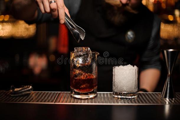 酒吧间销售酒精饮料的人投掷运动向一cockt一ilgl一ss一n冰立方形和镊子