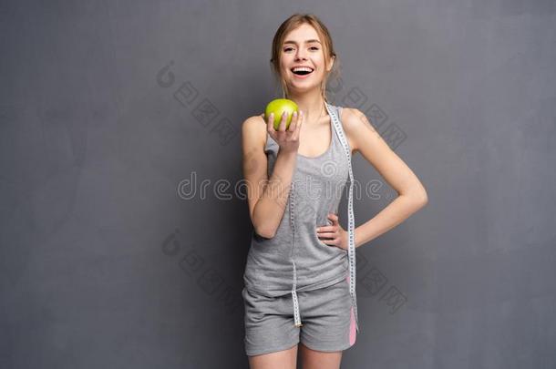 健康的女人看台和带子测量和绿色的苹果.健康的
