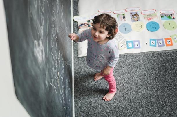 幼儿园观念.幸福的未满学龄的女孩绘画向黑板
