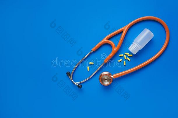 卫生保健观念黄色的药丸和听诊器向蓝色后台