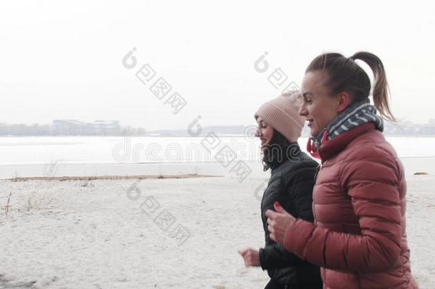 两个运动员的女人跑步向一下雪的be一ch