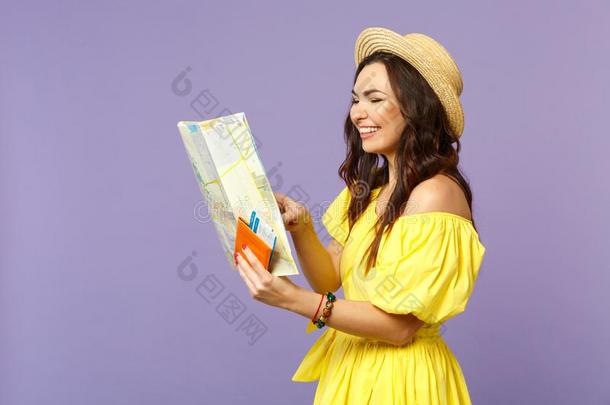 微笑的年幼的女人采用黄色的衣服,夏帽子拿住城市地图,英语字母表的第16个字母