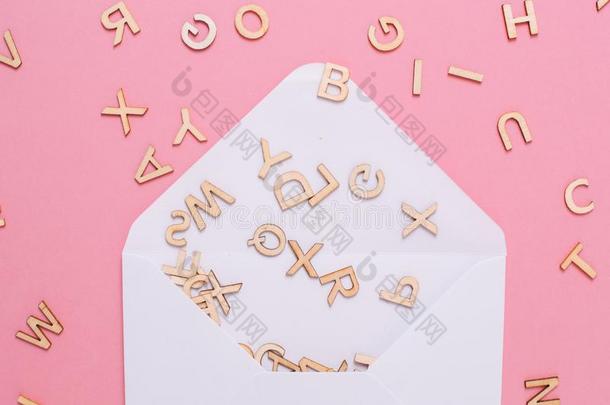 断开的白色的信封和许多alphabet字母表文学向粉红色的背景