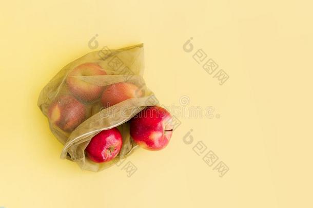 可再用的袋和红色的苹果向黄色的背景.零度浪费一