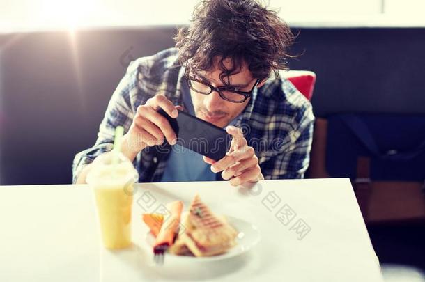 男人和智能手机摄影食物在咖啡馆