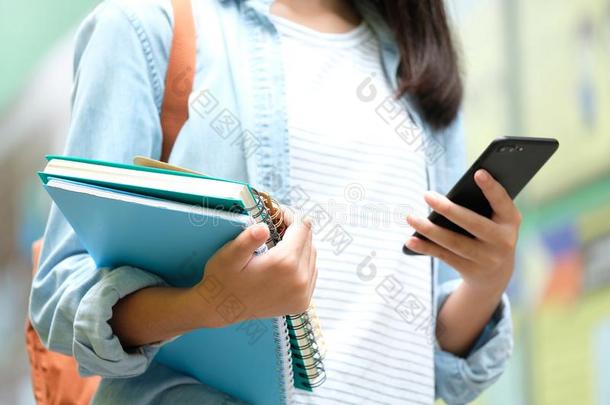 学生女孩佃户租种的土地书和使用智能手机,在线的教育