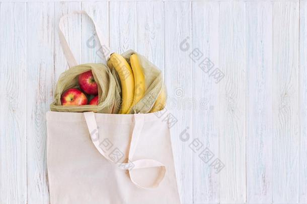 可再用的袋和苹果和香蕉向白色的木制的背景.