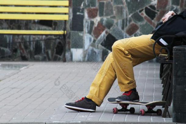 男人滑板运动员采用黄色的牛仔裤relax采用g向长凳.黄色的长凳