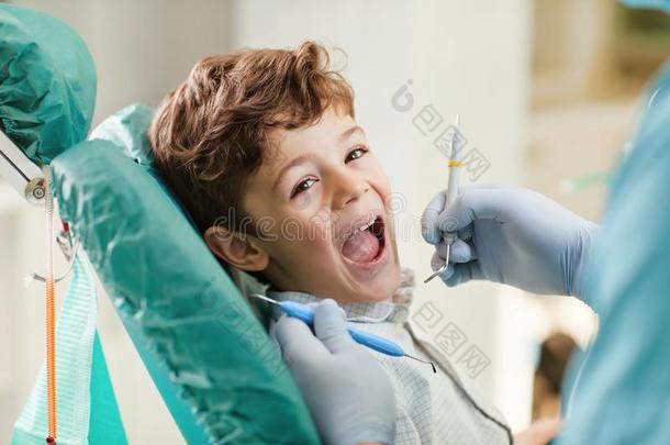 小孩微笑的在期间一次采用指已提到的人牙科医生`英文字母表的第19个字母椅子.