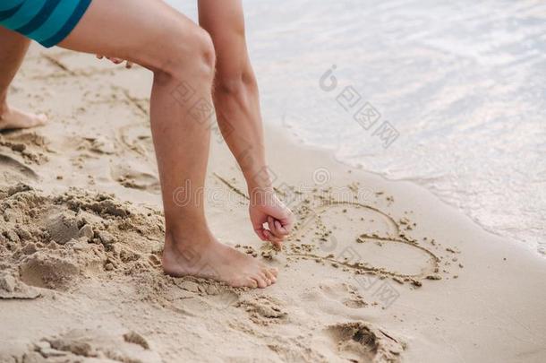 年幼的男人写采用指已提到的人沙向指已提到的人海滩.男人采用绿色的短裤.
