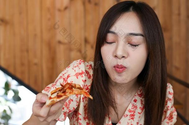 美丽的年幼的亚洲人女人吃美味的或很好吃的意大利薄饼