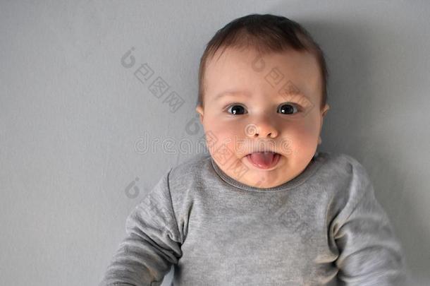 婴儿男孩采用灰色的衬衫给看指已提到的人舌头在期间ly采用g向床垫