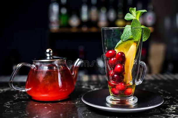 成果茶水和越橘,茶水pot和玻璃,黑暗的背景.