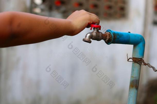 年幼的手旋转从落下一老的生锈的水轻敲为节约水-