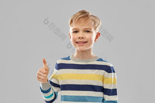 微笑的男孩采用有条纹的<strong>套衫</strong>show采用g拇指在上面