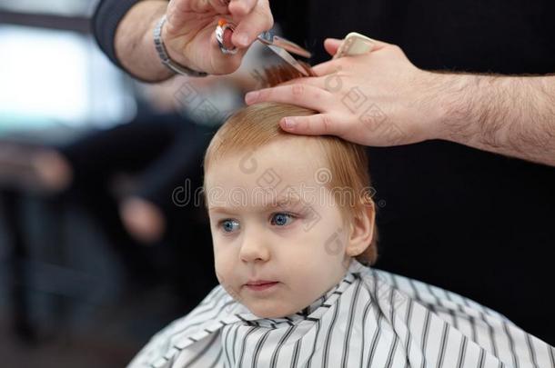 严肃的漂亮的亚麻色的婴儿男孩和蓝色眼睛采用一b一rber商店h一vi
