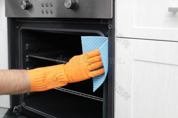年幼的男人清洁烤箱和破布采用厨房