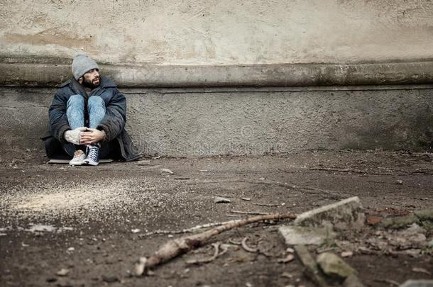 贫穷的无家可归的男人一次在近处墙向大街