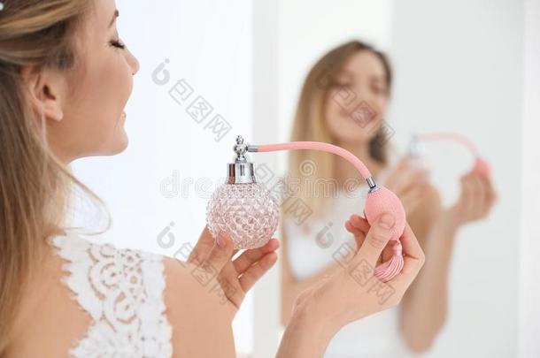 美丽的年幼的新娘和瓶子关于香水在近处镜子