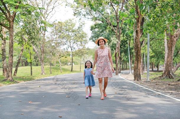 幸福的亚洲人妈妈和女儿步行向大街采用指已提到的人夏标准