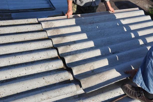 盖屋顶的人修理屋顶和开除石棉老的屋顶瓦片.屋顶盖法