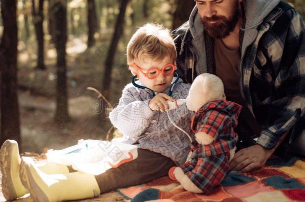 漂亮的男孩和鼻子擦拭者在近处秋树.父亲和小孩儿子